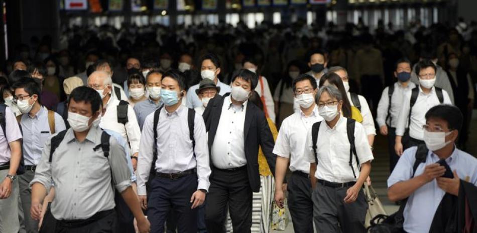 Pasajeros, con mascarilla para protegerse del coronavirus, caminan por un pasillo en plena hora punta, en la estación de Shinagawa, en Tokio.
