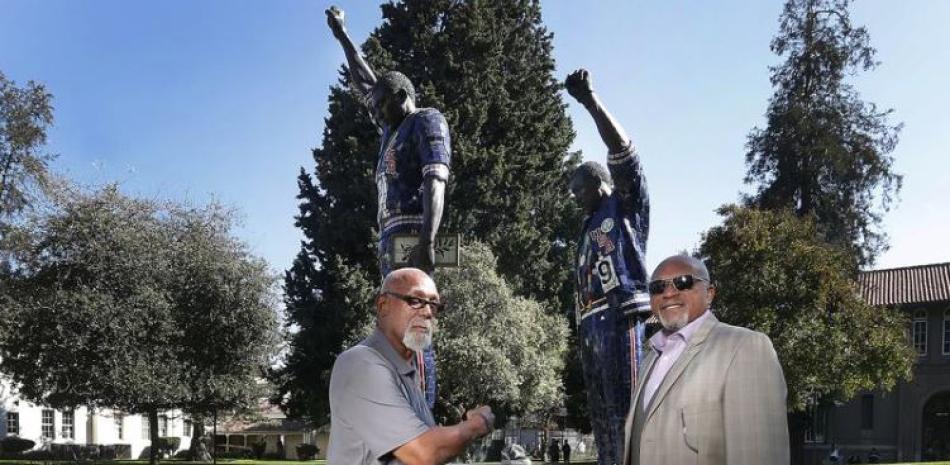 John Carlos y Tommie Smith posan frente a la estatua que los muestra con el puño en alto, la señal de protesta que hicieron en el podio de los Juegos Olímpicos de México 1968.