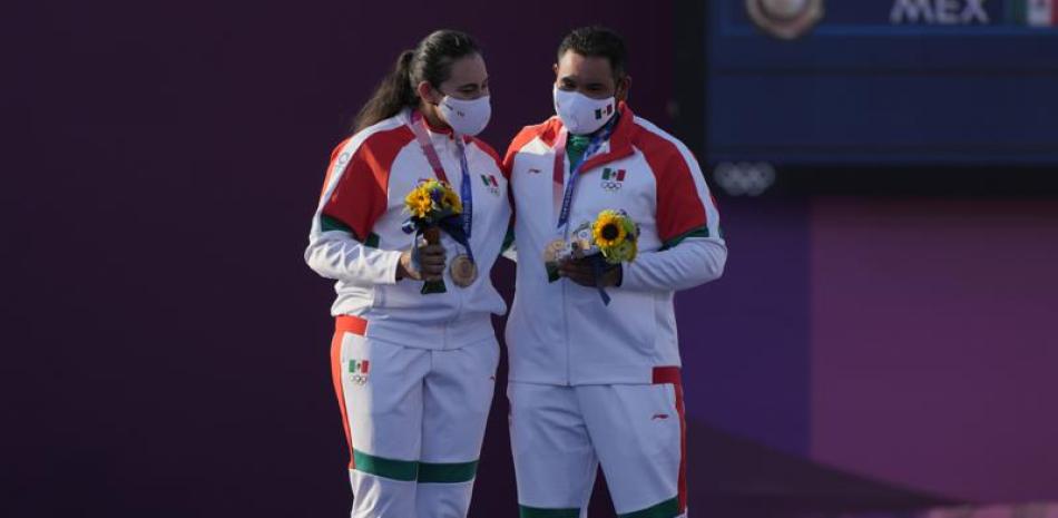 Los mexicanos Alejandra Valencia (izquierda) y Luis Álvarez celebran en el podio tras conseguir una medalla de bronce en la prueba mixta del tiro con arco de los Juegos Olímpicos de Tokio, el sábado 24 de julio de 2021. (AP Foto/Alessandra Tarantino)