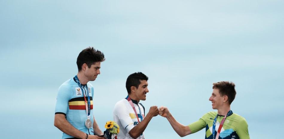El ecuatoriano Richard Carapaz, ganador de la medalla de oro, saluda al esloveno Tadej Pogacar, bronce, en el podio de la prueba de ruta de los Juegos Olímpicos de Tokio, el sábado 24 de julio de 2021, en Oyama. El belga Wout van Aert, plata, observa. (AP)