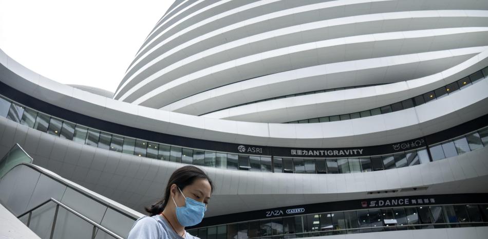 Una mujer con una mascarilla para protegerse del coronavirus camina en un complejo de tiendas y oficinas el martes 27 de julio de 2021, en Beijing.

Foto: AP Foto/Mark Schiefelbein