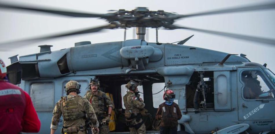En esta foto proporcionada por la Marina de los EE. UU., Los marineros asignados a una unidad de artefactos explosivos abordan un helicóptero MH-60S Seahawk en la cubierta de vuelo del portaaviones USS Ronald Reagan para dirigirse a un petrolero que fue atacado frente a las costas de Omán en Arabia. Sea el viernes 30 de julio de 2021. (Especialista en comunicación de masas de segunda clase, Quinton A. Lee / Marina de los EE. UU., Vía AP)