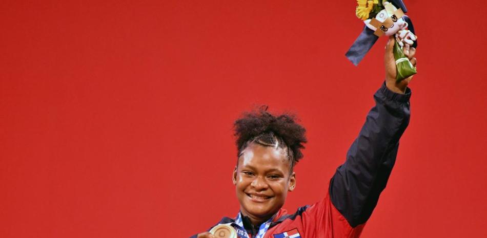 La dominicana Crismery Santana levanta su mano en señal de triunfo después de colgarse medalla de bronce en la categoría de los 87 kilogramos femeninos del torneo de levantamiento de pesas de los Juegos Olímpicos de Tokio.