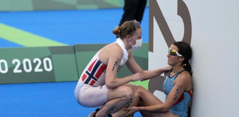 En esta imagen del 27 de julio de 201, la belga Claire Michel recibe la ayuda de la noruega Lotte Miller al concluir el triatlón individual, en Tokio.