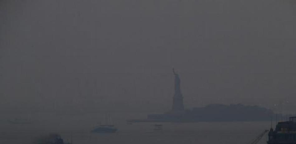 El ferry Staten Island sale de una terminal en Manhattan a través de una capa de humo con la Estatua de la Libertad de fondo, el martes 20 de julio de 2021 en Nueva York. (AP Photo/Julie Jacobson)