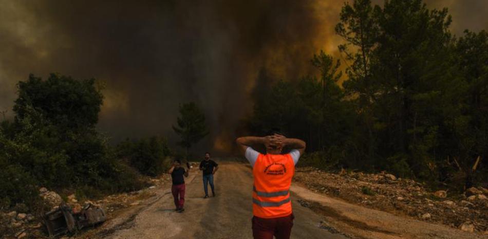 Unas personas corren lejos del poblado de Sirtkoy, en Antalya, Turquía, el domingo 1 de agosto de 2021, luego de que fue devastado por un incendio forestal. (AP Foto)