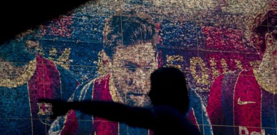 La foto del jueves 5 de agosto de 2021, muestra a contraluz la estatua de Johan Cruyff, frente a un mural de Lionel Messi en el Camp Nou de Barcelona.