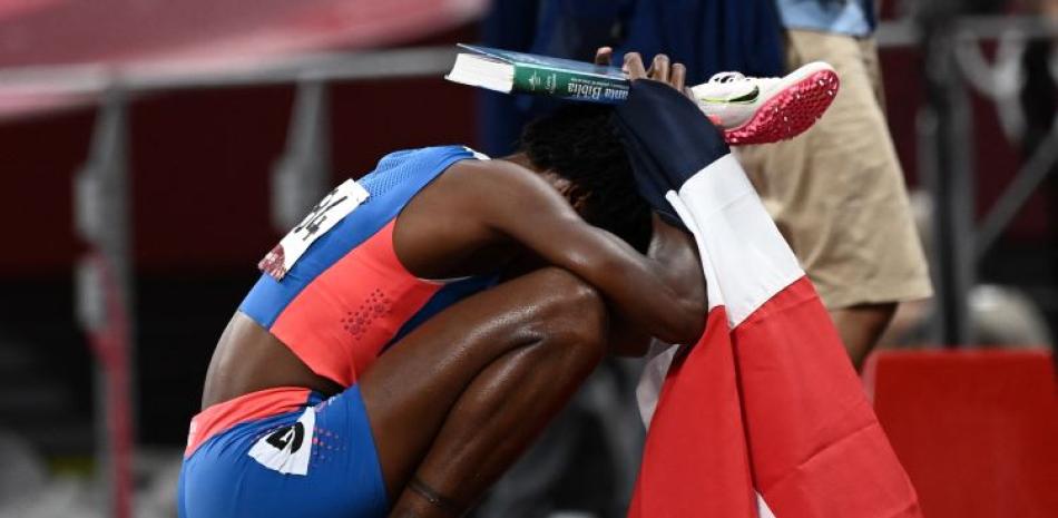 Marileidy Paulino sostiene la biblia y la bandera dominicana luego de ganar la medalla de plata en los 400 metros del torneo de atletismo de los Juegos Olímpicos Tokio 2020.