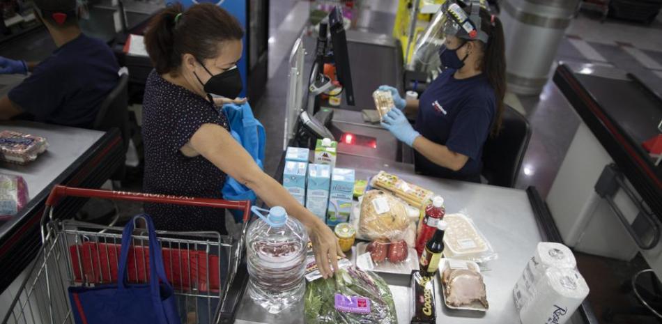 Una mujer pasa por la caja en un supermercado de Caracas el 4 de junio del 2021. Ya no hay escasez de productos en los supermercados de Venezuela, pero no mucha gente puede pagar los altos precios que se cobran, sobre todo si no tienen dólares y dependen del devaluado bolívar, la divisa nacional. (AP Photo/Ariana Cubillos)