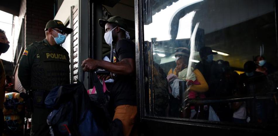 Un policía vigila hoy el ingreso de migrantes haitianos a un bus, en Cali (Colombia). Durante varios días, cientos de haitianos permanecieron en la capital vallecaucana debido a que autoridades migratorias colombianas les impedían el tránsito al ingresar de manera irregular al país. Pero este viernes cerca de 300 migrantes fueron autorizados a seguir su recorrido hacia Medellín para luego ir a la frontera entre Colombia y Panamá. EFE/ Ernesto Guzmán Jr