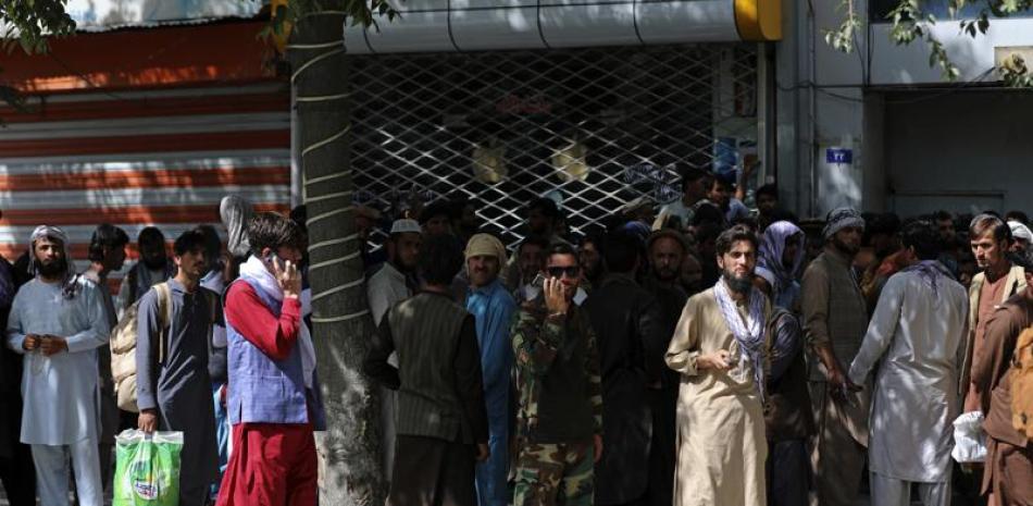 Afganos hacen largas filas el domingo 15 de agosto de 2021 para retirar dinero de un banco, en Kabul, Afganistán. (AP Foto/Rahmat Gul)