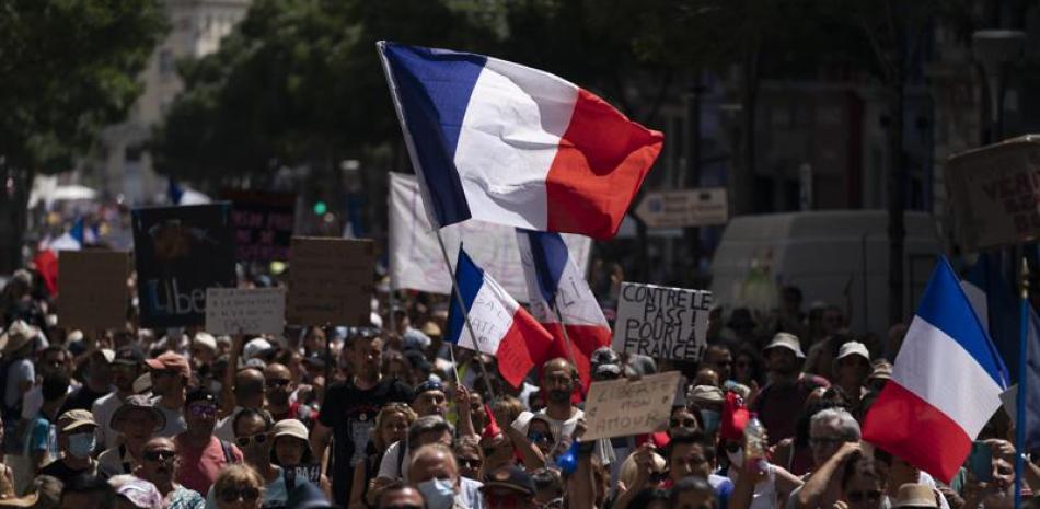 Manifestantes marchan por Marsella, Francia, sábado 14 de agosto de 2021, contra el pasaporte COVID-19, una certificación obligatoria para entrar a restaurantes, trenes de alta velocidad y otros recintos. (AP Foto/Daniel Cole)