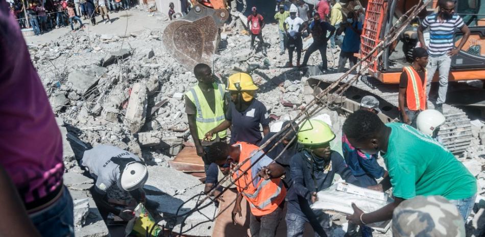 La gente busca sobrevivientes entre los escombros en el barrio de Dexia 6, Les Cayes, Haití, el 15 de agosto de 2021, luego de que un terremoto de magnitud 7.2 sacudiera la península suroeste del país.

Foto: REGINALD LOUISSAINT JR / AFP