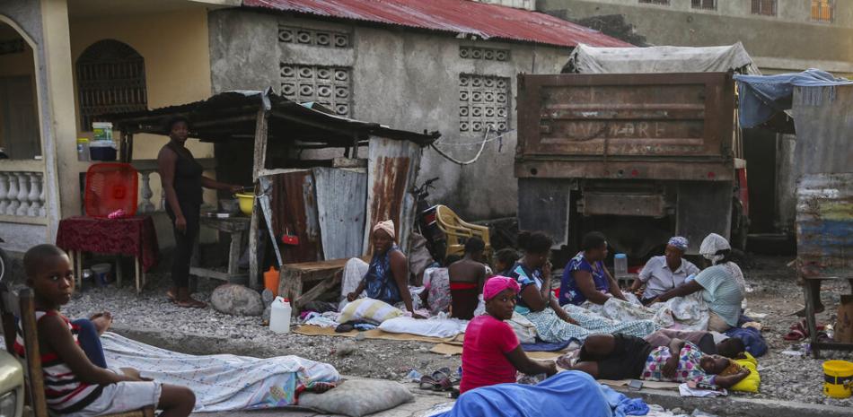 Un grupo de personas empiezan a despertar el domingo 15 de agosto de 2021 luego de pasar la noche en la calle tras un sismo de magnitud 7,2 en Los Cayos, Haití. (AP Foto/Joseph Odelyn)