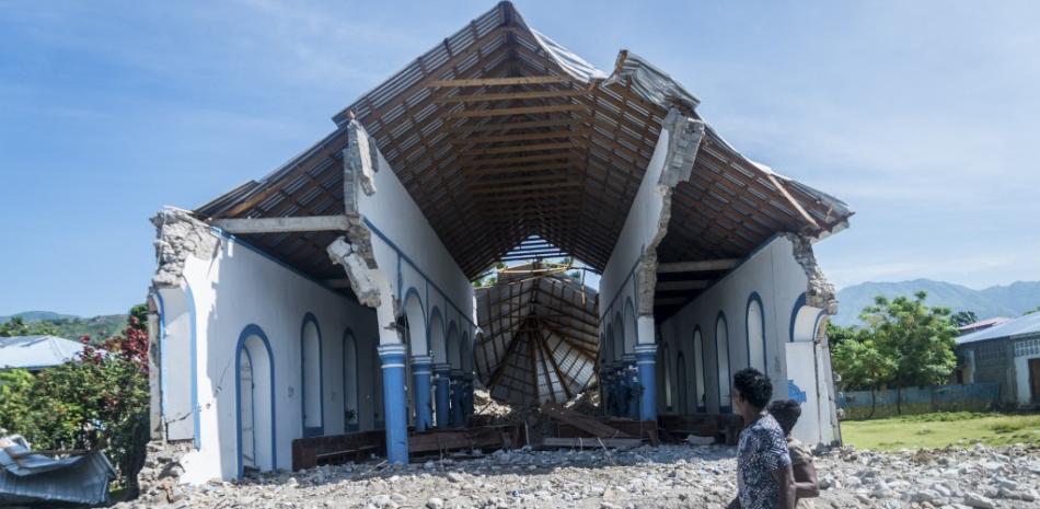 Dos haitianos pasan junto a una iglesia destruida durante un terremoto en Les Anglais el 14 de agosto de 2021.

Foto: REGINALD LOUISSAINT JR / AFP