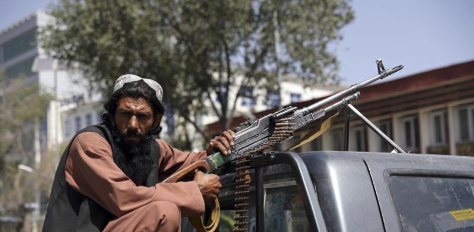 Un combatiente del Talibán apostado con una ametralladora frente al principal ingreso al palacio presidencial en Kabul (Afganistán). (AP Photo/Rahmat Gul)