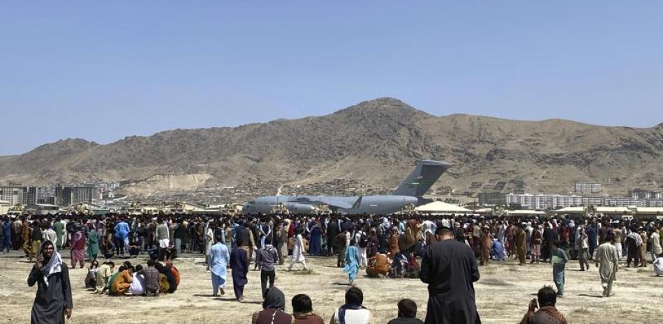 Cientos de personas esperan junto a un avión de transporte C-17 de la Fuerza Aérea de Estados Unidos en el perímetro del aeropuerto internacional de Kabul, Afganistán, el 16 de agosto de 2021. (AP Foto/Shekib Rahmani)