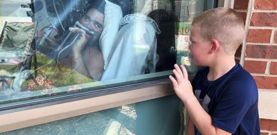 En esta imagen del 26 de julio de 2021, Brody Barker saluda a su papá, Daryl, desde el exterior de su cuarto de hospital en Osage Beach, Missouri, mientras se recupera de COVID-19. (AP Foto/Sarah Blake Morgan, Archivo)