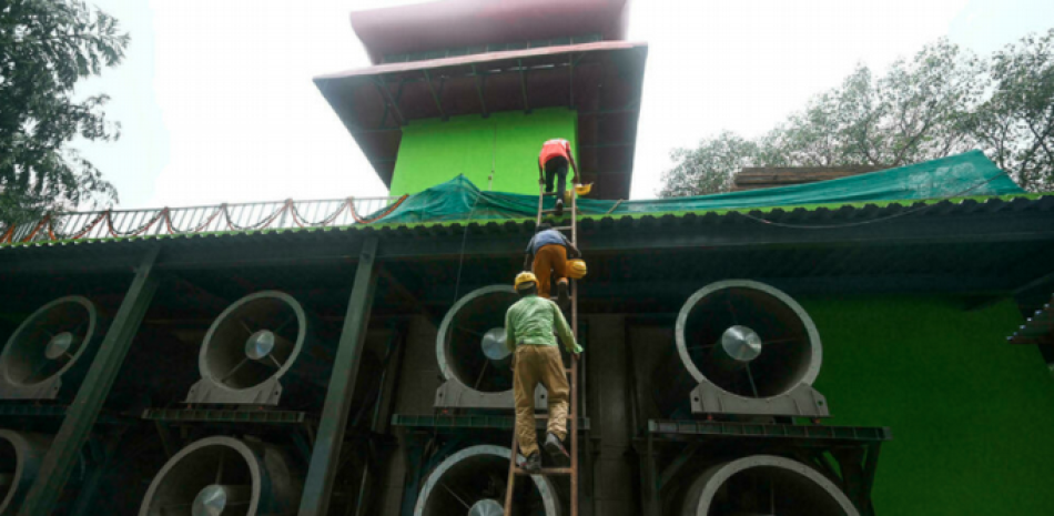 Trabajadores suben a una torre de 25 metros construida en Nueva Delhi para purificar el aire contaminado, el 23 de agosto de 2021 Money SHARMA AFP