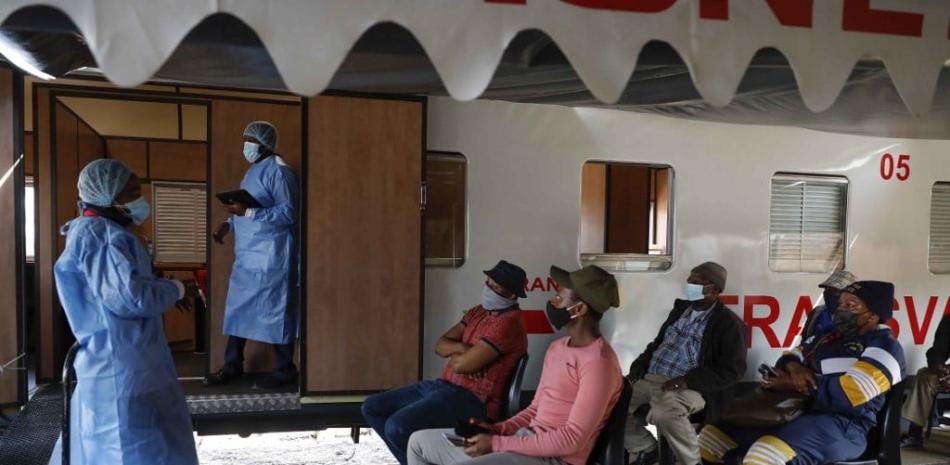 Los trabajadores de la salud informan a las personas que hacen cola para recibir sus vacunas sobre las diferentes vacunas disponibles para administrar fuera del tren de vacunas Transvaco Covid-19 estacionado en la estación de tren de Springs en las afueras de Johannesburgo, el 25 de agosto de 2021. La función de Transvaco es simplemente administrar las vacunas Covid-19 a comunidades que tienen recursos sanitarios limitados. Phill Magakoe / AFP