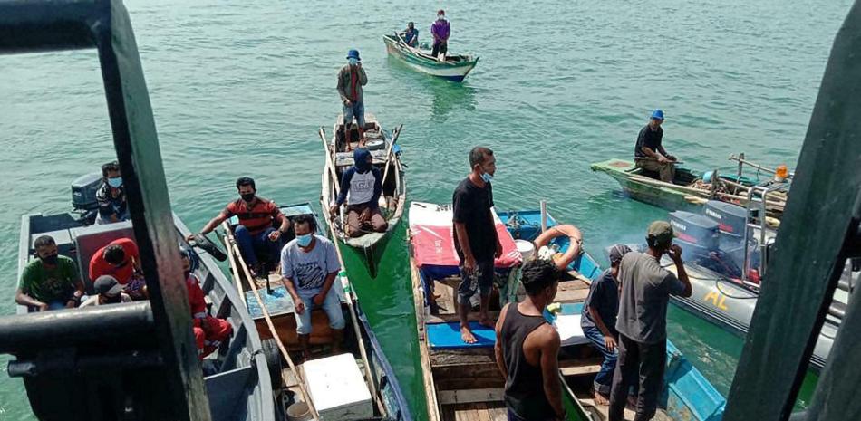 Foto tomada por la marina indonesia el 21 de agosto de 2021, brindada a la prensa el día 25, mostrando a botes de pescadores y pequeños barcos pesqueros acercándose a un buque para vacunar a sus ocupantes. HANDOUT INDONESIAN NAVY/AFP