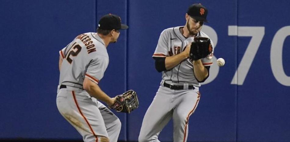 Alex Dickerson, a la izquierda, y Austin Slater, a la derecha, de los Gigantes de San Francisco, colisionan y no atrapan la bola conectada por Brandon Drury, de los Mets.