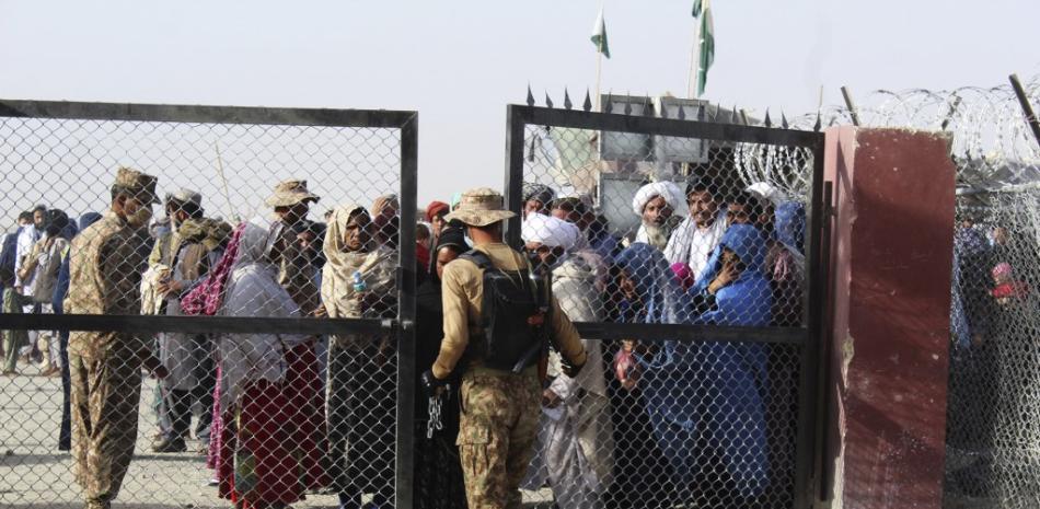 A Pakistani soldier holds a gate as Afghan and Pakistani people wait to enter Afghanistan through the Pakistan-Afghanistan border crossing point in Chaman on August 27, 2021 following the Taliban's stunning military takeover of Afghanistan.

Foto: AFP