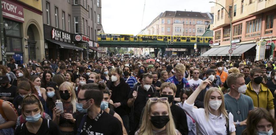 Manifestantes, la mayoría con mascarillas, bailan detrás de un camión durante una marcha llamada "Tren del Amor" en Berlín, Alemania, el sábado, 28 de agosto del 2021. Los manifestantes se oponen al movimiento contra las restricciones por la pandemia. (AP Foto/Markus Schreiber)