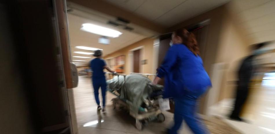 En esta imagen del miércoles 18 de agosto, personal médico traslada a una persona que murió de COVID-19 hacia un muelle de carga para ser colocado en vehículo funerario, en el Centro Médico Willis-Knighton en Shreveport, Luisiana. (AP Foto/Gerald Herbert, Archivo)