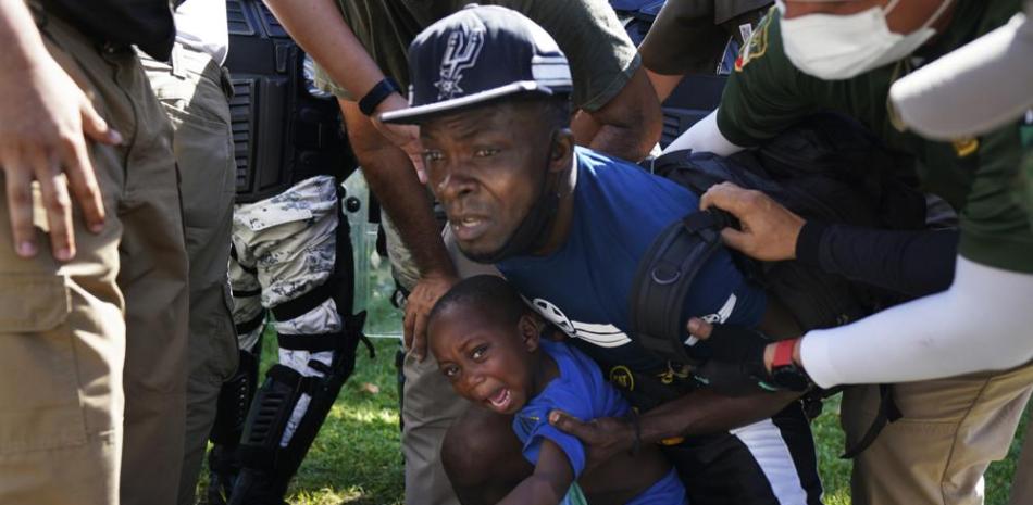 La Guardia Nacional Mexicana detiene a un migrante haitiano y a su hijo mientras caminaban por una carretera en Escuintla, estado de Chiapas, México, el jueves 2 de septiembre de 2021, en su viaje hacia Estados Unidos. (AP Foto/Marco Ugarte)