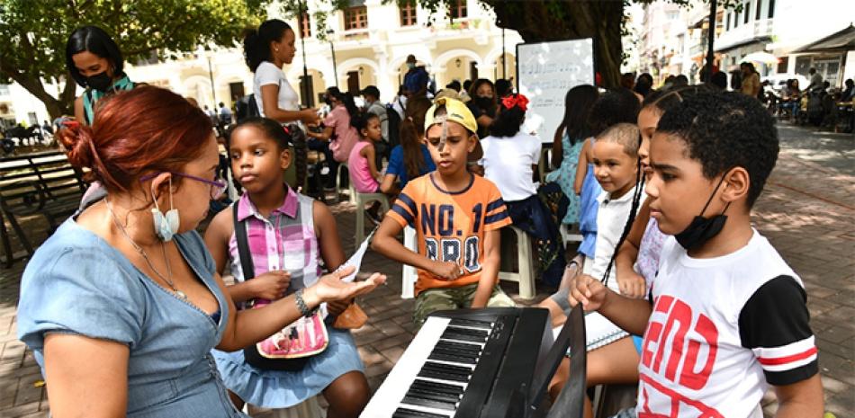 APRENDIENDO EN EL PARQUE. Niños reciben instrucción de música impartida por profesores voluntarios en el Parque Colón de la Ciudad Colonial de Santo Domingo, donde funciona una escuela que se inició con clases de guitarra y hoy acoge a 300 estudiantes asistidos por 38 músicos.