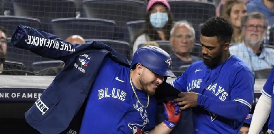 Teoscar Hernández ayuda a colocar la chaqueta a Alejandro Kirk, su compañero en los Azulejos de Toronto, quien conectó un jonrón ante los Yanquis de Nueva York.