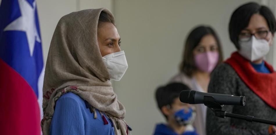 Zainab Momeny, quien era profesora universitaria en Afganistán, habla durante una conferencia de prensa mientras su hermana Zahar mira, a la derecha, poco después de aterrizar en el aeropuerto de Santiago, Chile, el viernes 10 de septiembre de 2021. (AP Foto/Esteban Félix)