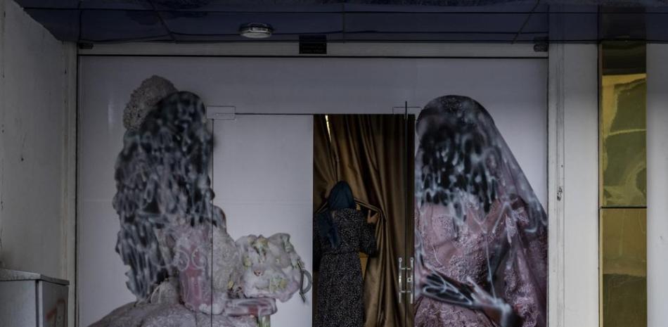 Una mujer ingresa en un salón de belleza en Kabul, Afganistán, el sábado 11 de septiembre de 2021. Desde que los talibanes asumieron el control del gobierno, diversas imágenes sobre mujeres en el exterior de salones de belleza fueron retirados o cubiertos. (AP Foto/Bernat Armangue)