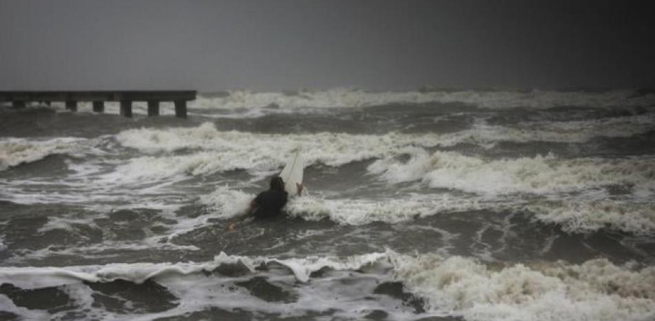 Un surfista intenta remar entre las olas mientras el viento y la lluvia de la tormenta tropical Nicholas golpea la zona, el lunes 13 de septiembre de 2021, junto al dique en Galveston, Texas. (Jon Shapley/Houston Chronicle via AP)