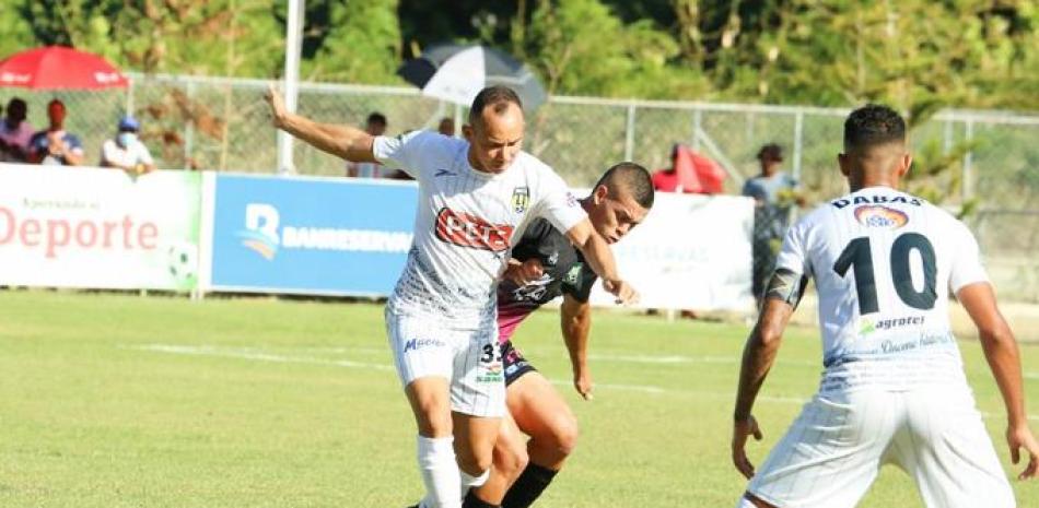 Rafael Padilla, de Moca FC, trata de proteger el balón de uno de los jugadores de Jarabacoa durante el encuentro de este sábado celebrado en el estadio Junior Mejía.