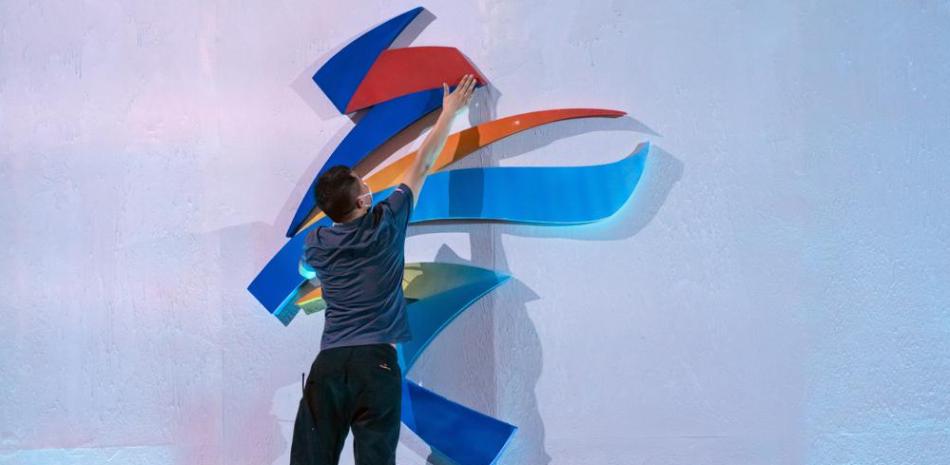 Un miembro del personal salta para reacomodar un logo de los Juegos Olímpicos de Invierno Beijing 2022 antes de una ceremonia de lanzamiento para revelar el lema de los Juegos Olímpicos y Paralímpicos de Invierno, en Beijing.