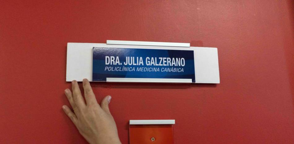 Una enfermera muestra un letrero personalizado en la puerta de la oficina de la Dra. Julia Galzerano con una descripción que dice "Policlínica medicina canábica", en el hospital CASMU en Montevideo, Uruguay, el viernes 17 de septiembre de 2021. (AP Foto/Matilde Campodónico)