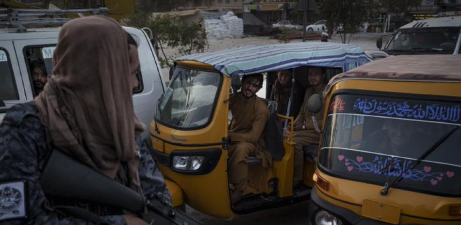 Conductores y pasajeros afganos en el tráfico ven a combatientes del Talibán en la parte trasera de una camioneta, el lunes 20 de septiembre de 2021, en Kabul. (AP Foto/Felipe Dana)