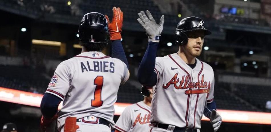 El jugador de los Bravos de Atlanta Freddie Freeman choca con Ozzie Albies (1) tras pegar un jonrón de dos carreras en el noveno inning en Phoenix.