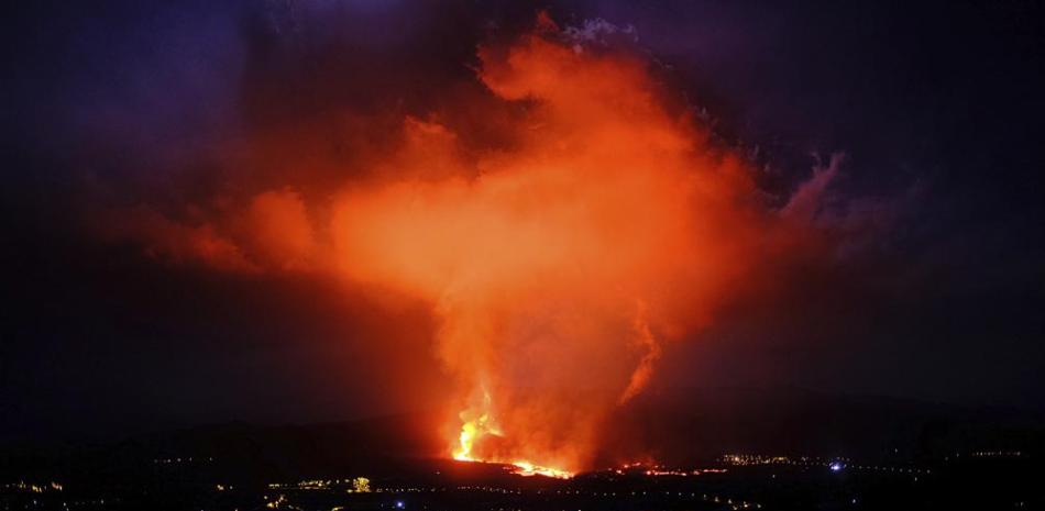 Dos personas caminan durante la noche mientras un volcán expulsa lava, en La Palma, Islas Canarias, el 25 de septiembre de 2021. (AP Foto/Daniel Roca)