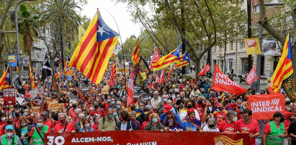 Los manifestantes ondean banderas independentistas catalanas "Estelada" y sostienen una pancarta que dice "Luchamos y ganamos la independencia" durante una manifestación que celebra el cuarto aniversario del referéndum independentista prohibido, en Barcelona, el 3 de octubre de 2021. Josep Lago / AFP