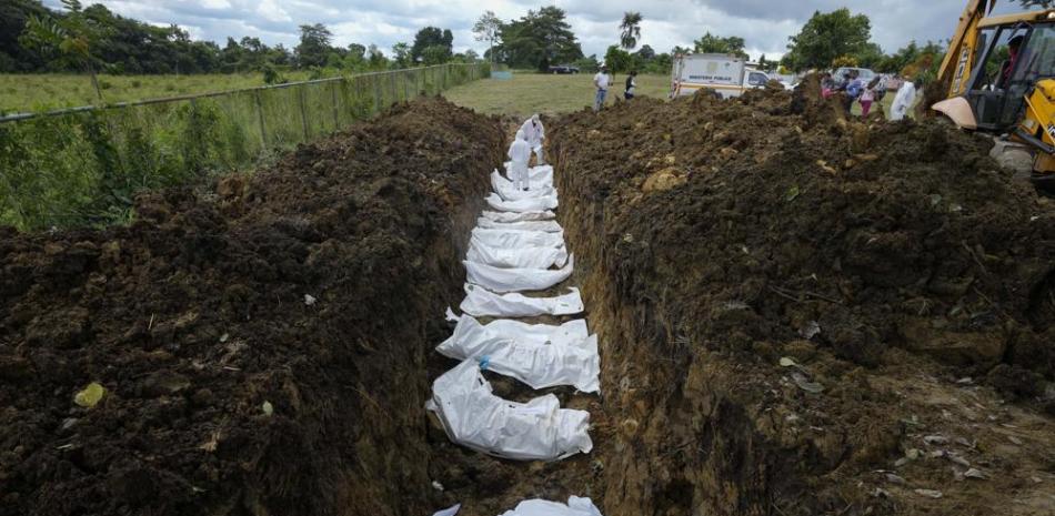 Equipo forense entierra a un grupo de migrantes que murieron tratando de cruzar la brecha del Darién, en una fosa común en el cementerio de Guayabillo en Agua Fría, Panamá, el jueves 30 de septiembre de 2021. (Foto AP/Arnulfo Franco)