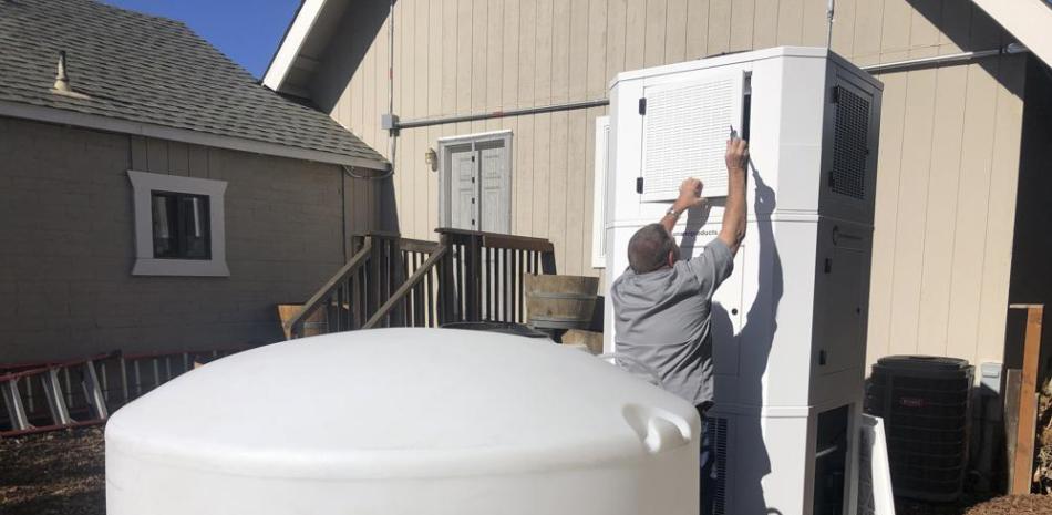 Ted Bowman, ingeniero de Tsunami Products, instala una máquina que puede obtener agua del aire en el patio de la vivienda de Don Johnson / Foto AP