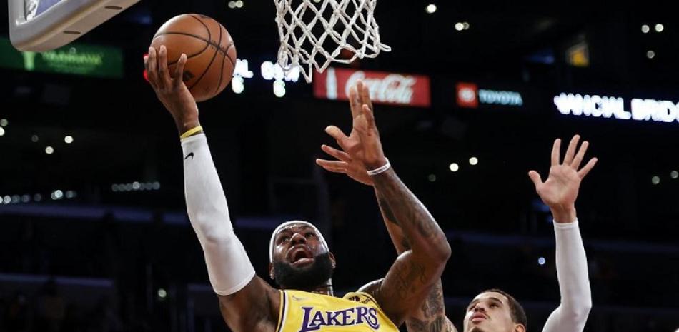 El alero de los Lakers LeBron James va con el balón hacia la canasta mientras lo defiende Juan Toscano-Anderson de los Warriors en un juego de pretemporada.