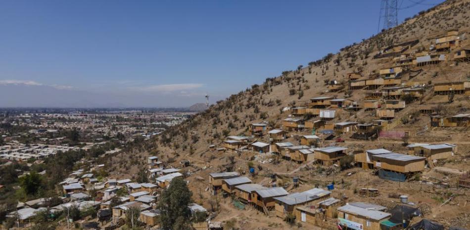 Las casas se encuentran en la ladera de una colina en un área sin pavimentar llamada "Bosque Hermoso", donde migrantes de Haití, Perú y Colombia se establecieron en Lampa, Chile, el viernes 1 de octubre de 2021. (AP Foto/Esteban Felix)