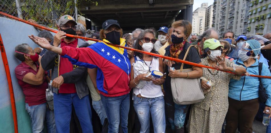 En esta imagen de archivo, tomada el 16 de septiembre de 2021, residentes esperan detrás de una cinta que sirve de barrera ante un centro de vacunación, donde buscan recibir la segunda dosis de la rusa Sputnik V contra el COVID-19, en Caracas, Venezuela.

Foto: AP/Ariana Cubillos