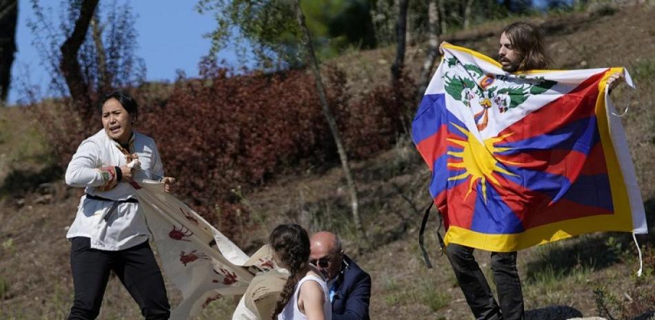 Un policía intenta detener a manifestantes que muestran una bandera tibetana y una pancarta con el mensaje "No a los juegos del genocidio".
