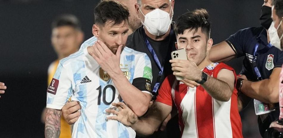 Lionel Messi se retira de la cancha mientras un aficionado se toma una selfie al final del partido contra Paraguay por las eliminatorias de la Copa Mundial.
