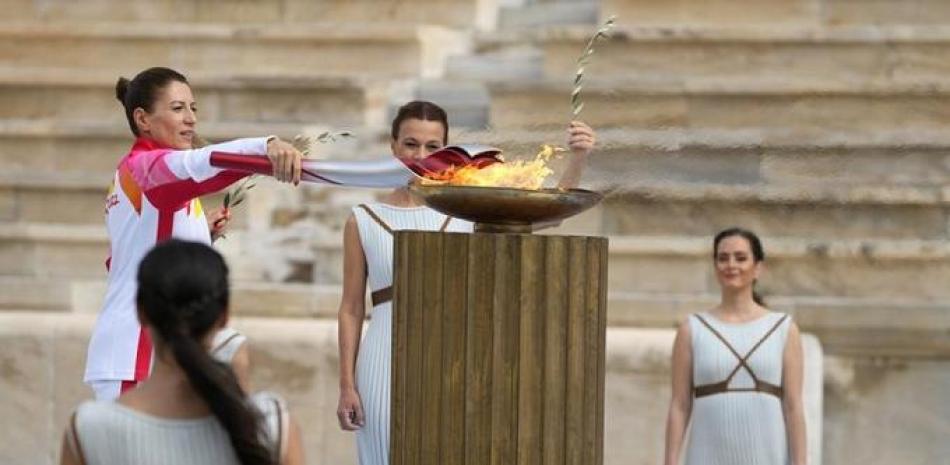 La campeona griega de esquí Paraskevi Ladopoulou enciende la antorcha durante la ceremonia de entrega de la llama olímpica, en el estadio Panathinean, en Atenas.